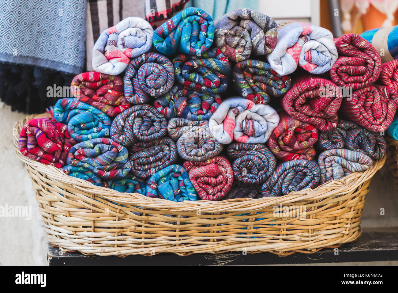 Rotoli di asciugamani multicolore in un cesto di vimini nella vetrina di un negozio Foto Stock