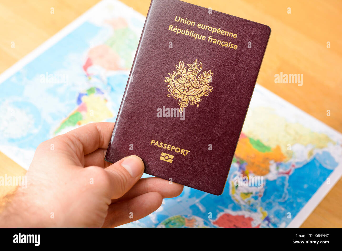 Passaporto in mano con un mondo di mappe in background Foto Stock