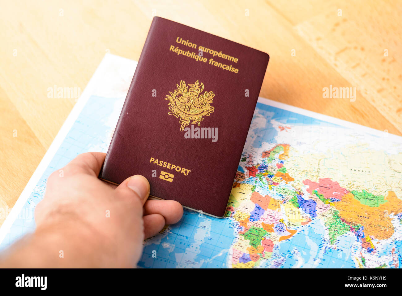 Passaporto in mano con un mondo di mappe sul tavolo Foto Stock