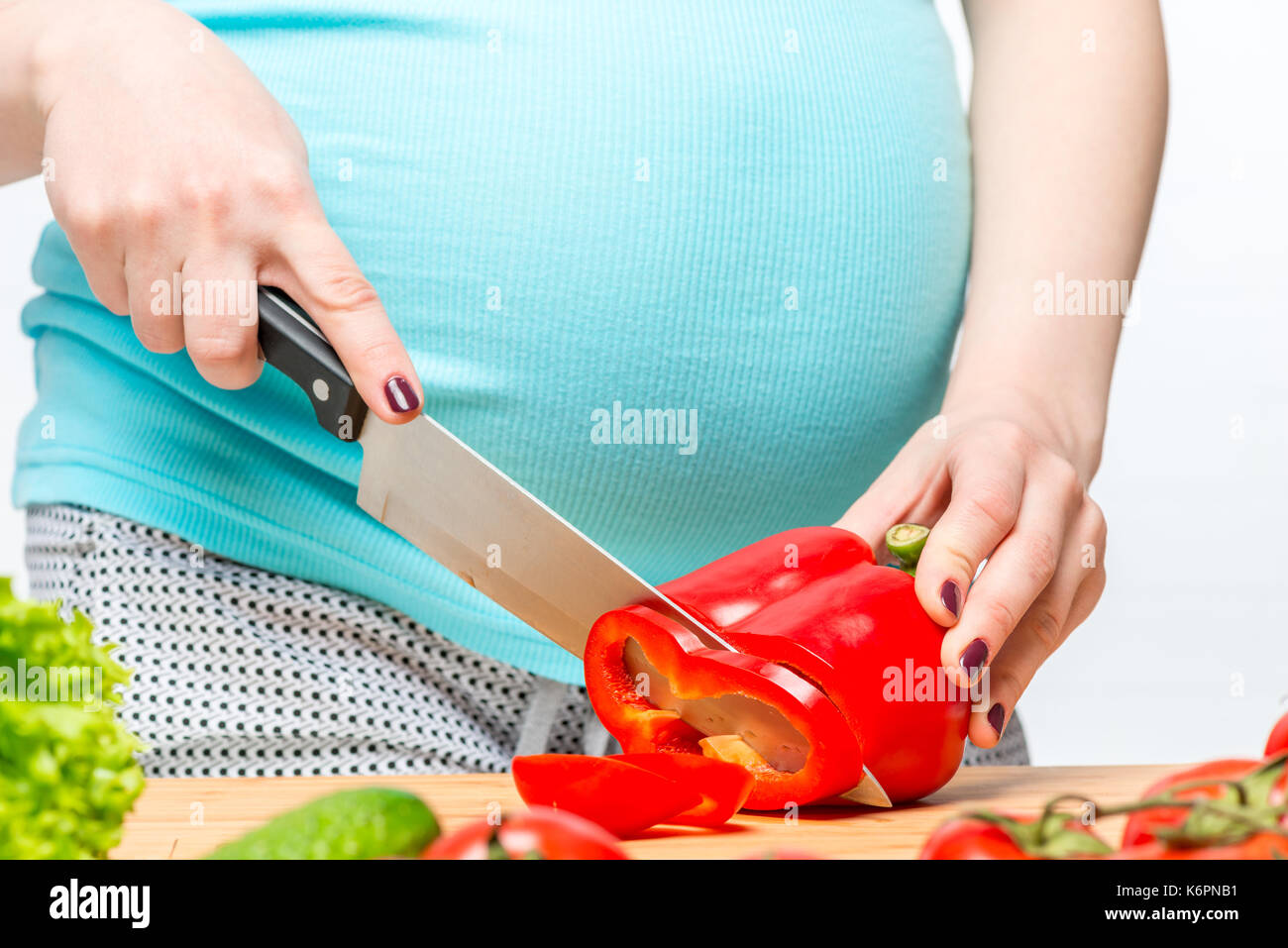 Close-up di una donna in stato di gravidanza la mano a preparare un'insalata di verdure Foto Stock