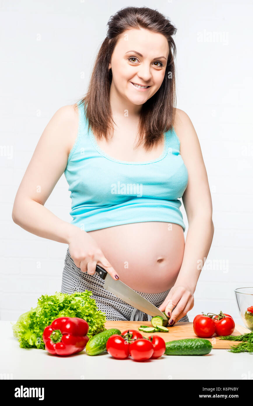 Felice donna incinta in cucina preparare un'insalata di verdure Foto Stock