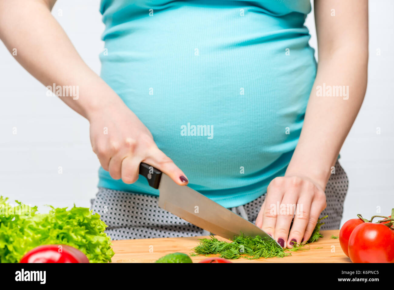 Donna incinta fette erbe fresche su un tagliere, mani close-up Foto Stock