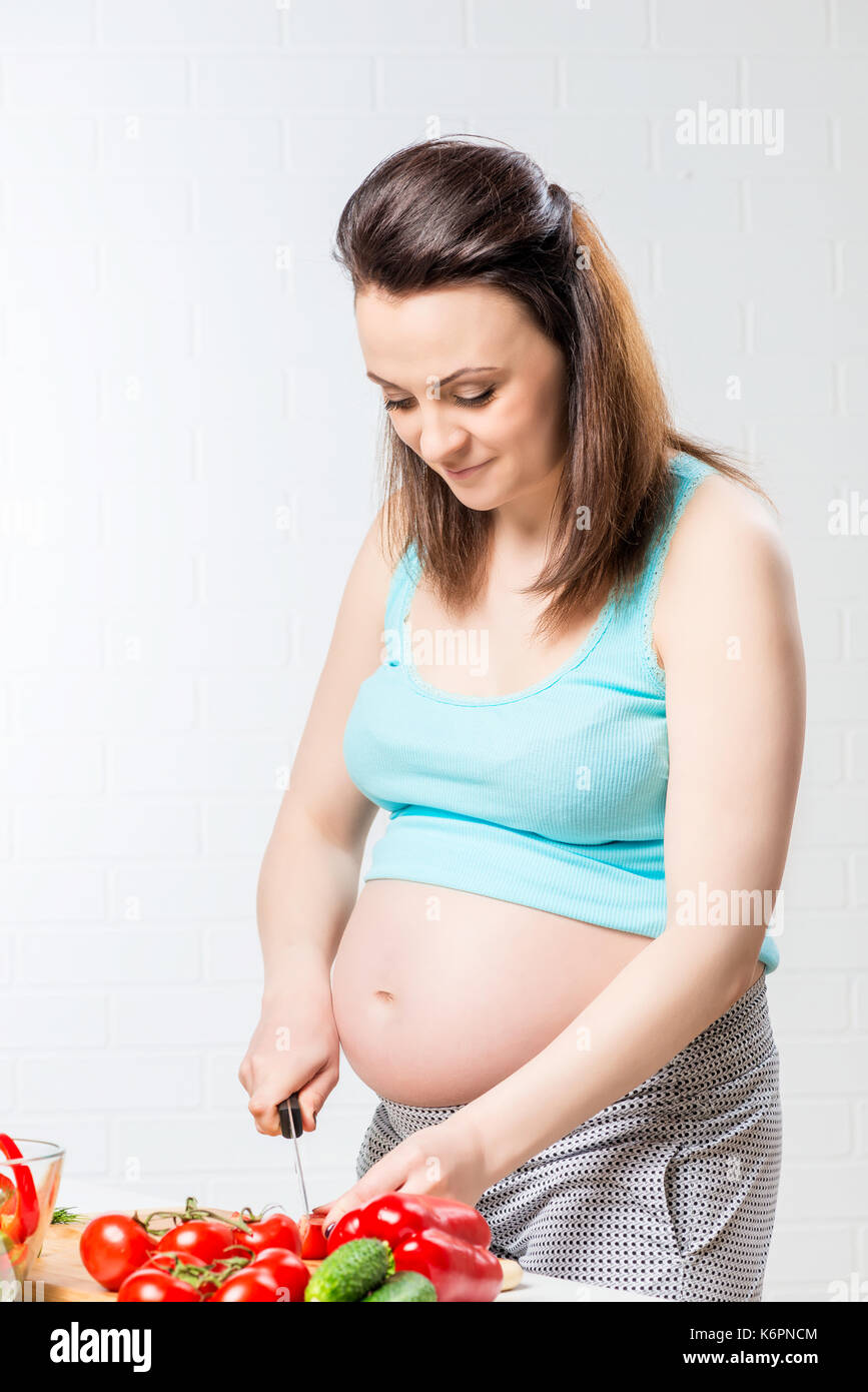 Bella ragazza incinta preparare un'insalata di verdure fresche Foto Stock