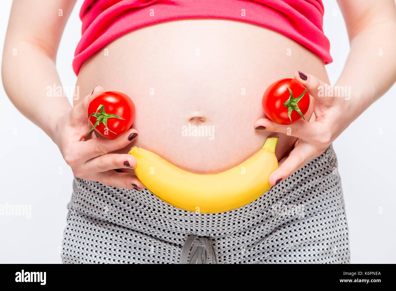 Funny foto di un sorriso di verdure e frutti sullo sfondo di una gravidanza ventre closeup Foto Stock