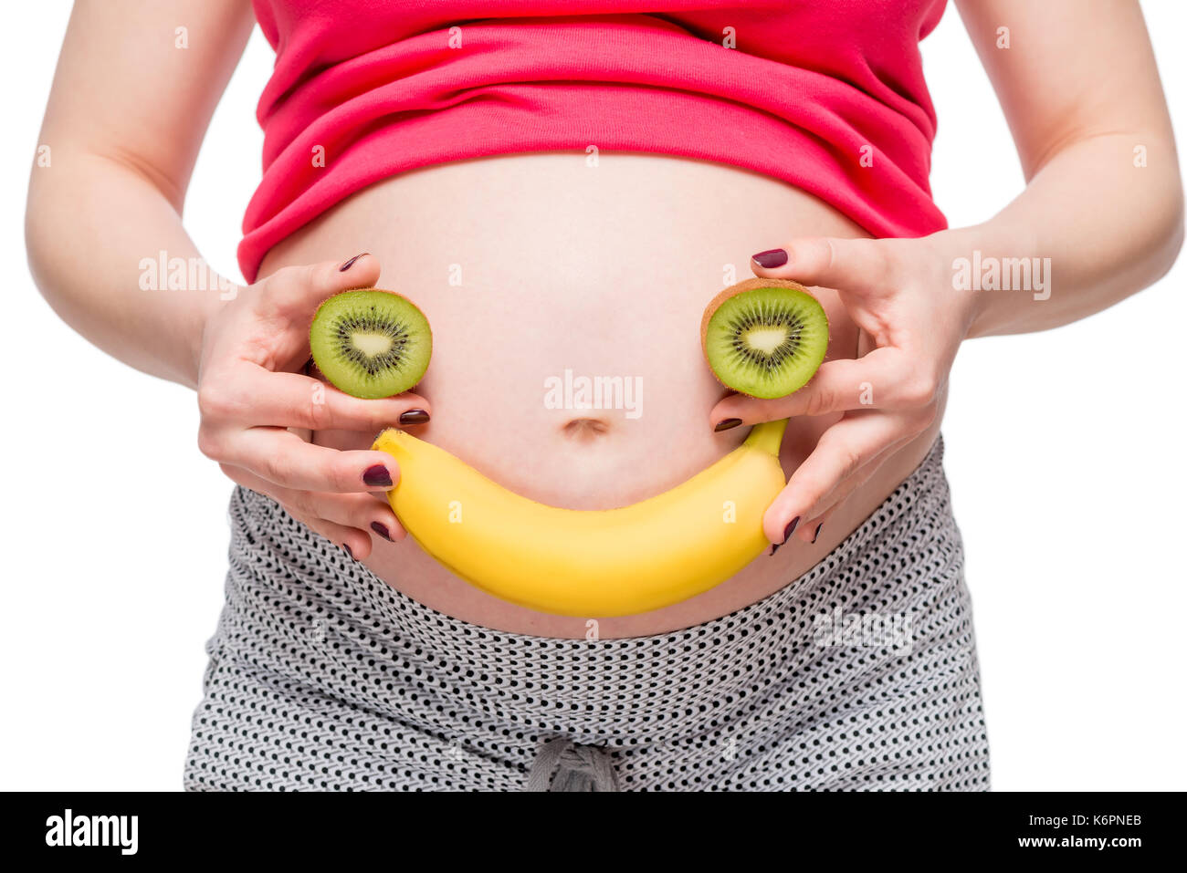 Foto concettuale - occhi e un sorriso di frutta sullo sfondo di una gravidanza pancia Foto Stock