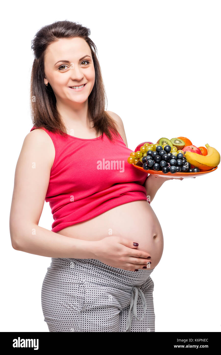 Una sana felice donna incinta con un piatto di frutta isolato ritratto Foto Stock