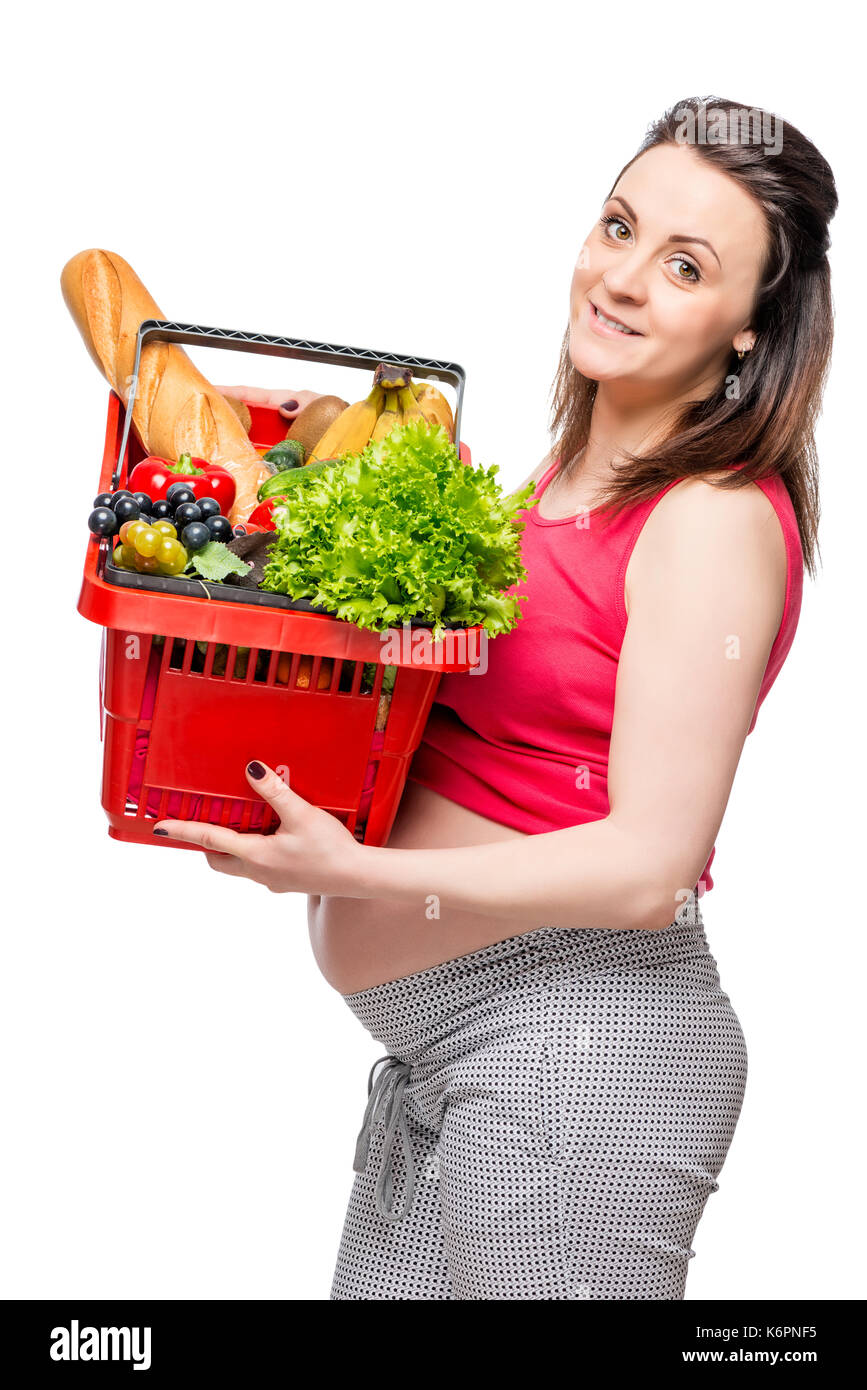 Ritratto verticale di una donna incinta con un paniere di prodotti utili isolato Foto Stock