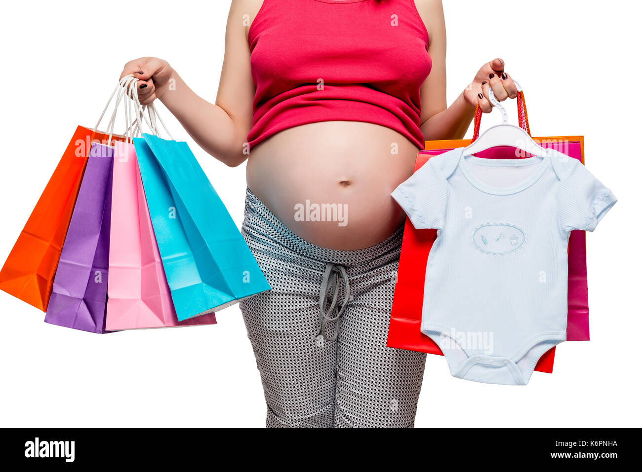 Abbigliamento per il suo figlio e gli altri acquisti nelle mani di una donna in stato di gravidanza, ventre closeup Foto Stock