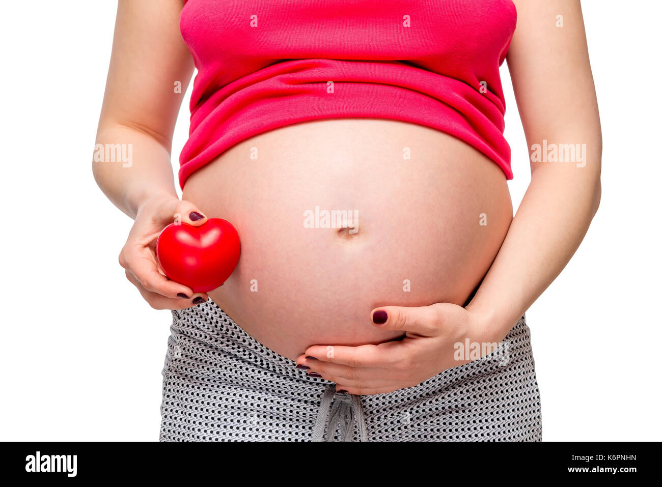 Close-up del ventre di una donna incinta con un cuore rosso forma - concetto foto Foto Stock