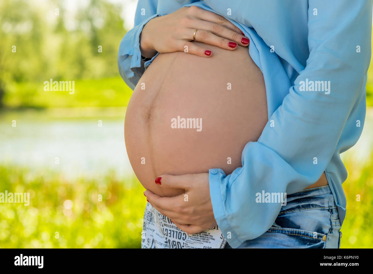 Bella grande pancia di una donna incinta di close-up, riprese nel parco Foto Stock