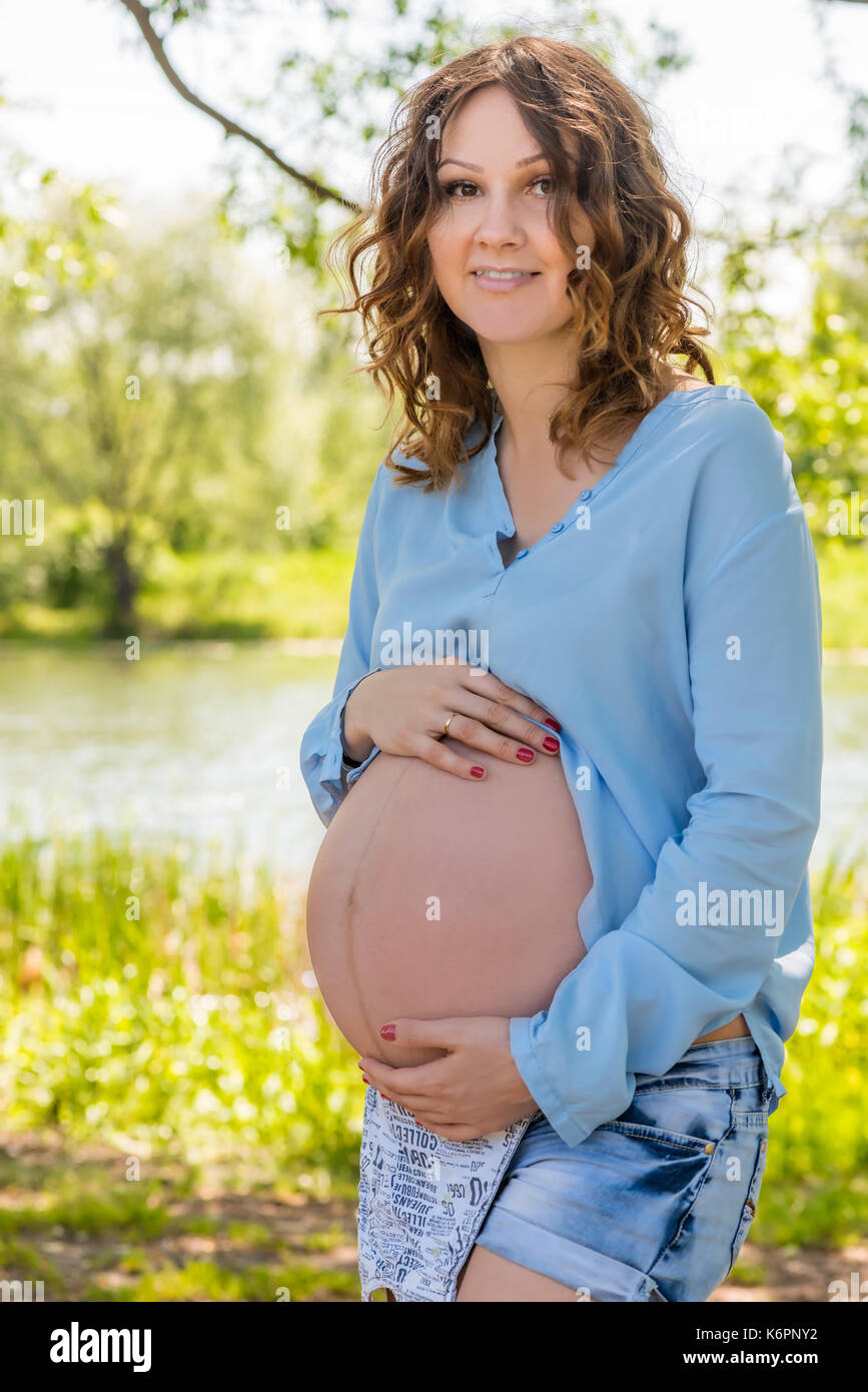 Ritratto di un futuro felice madre in un parco vicino al lago Foto Stock