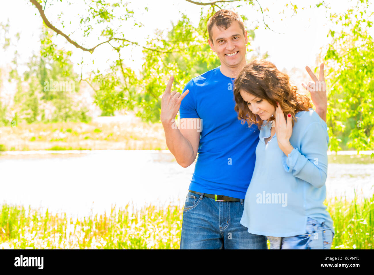 L'uomo e sua moglie incinta in un parco vicino al lago di posa Foto Stock