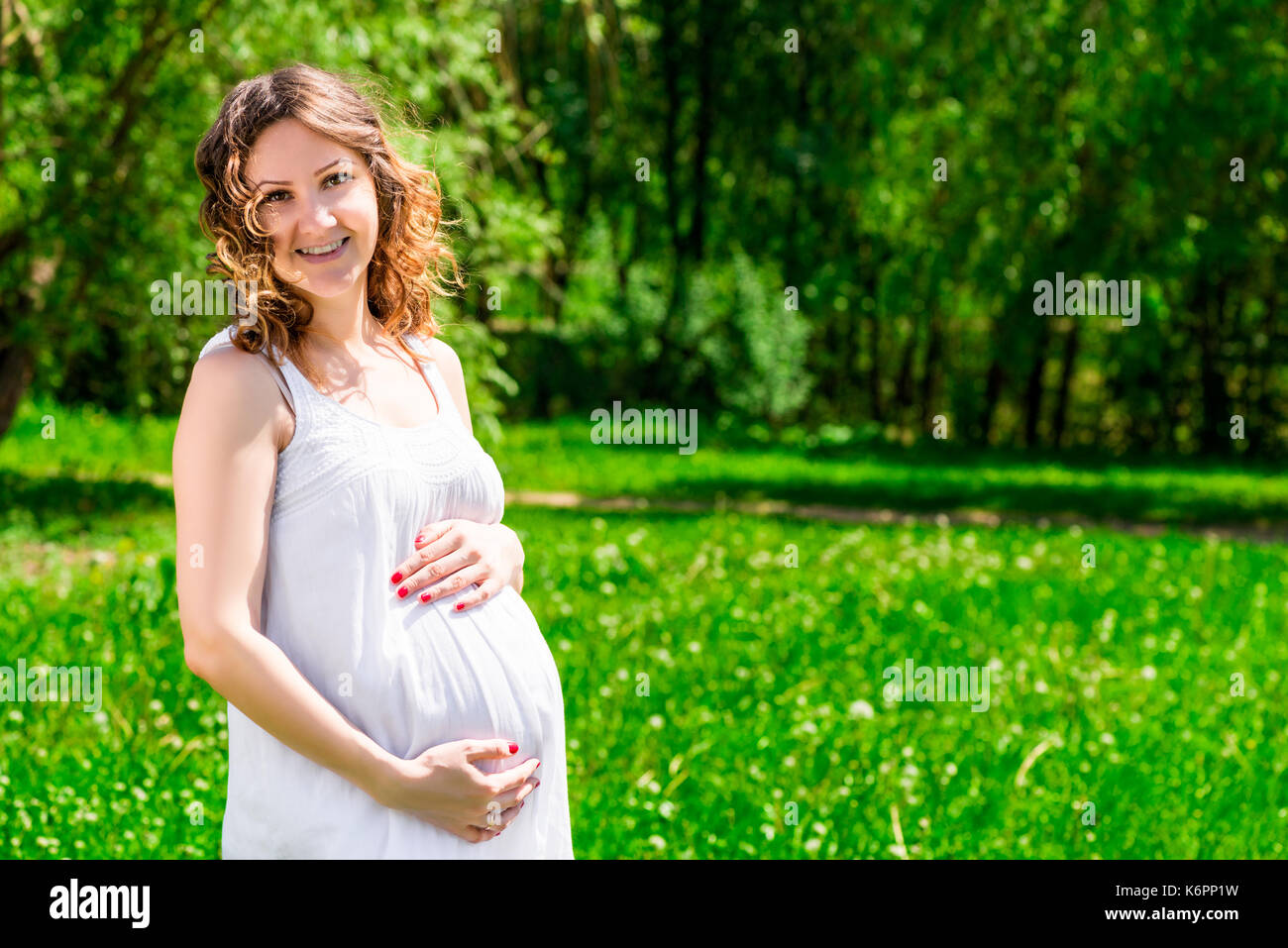 Ritratto di un futuro felice madre in attesa di un bambino in un parco verde Foto Stock