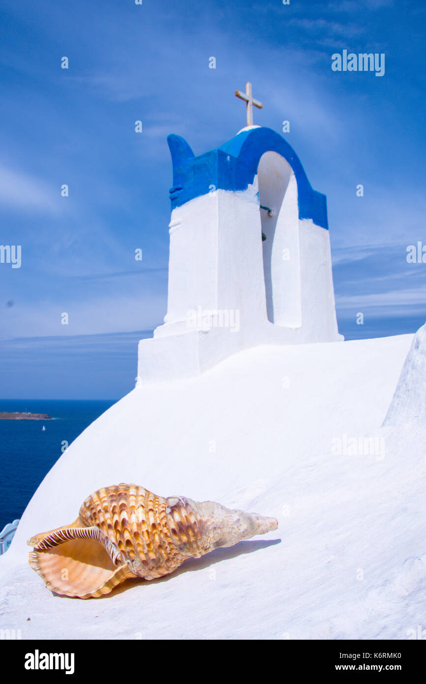 Il campanile di una chiesa ortodossa a Santorini con una conchiglia, Grecia. luna di miele estate egeo sullo sfondo delle Cicladi. Foto Stock