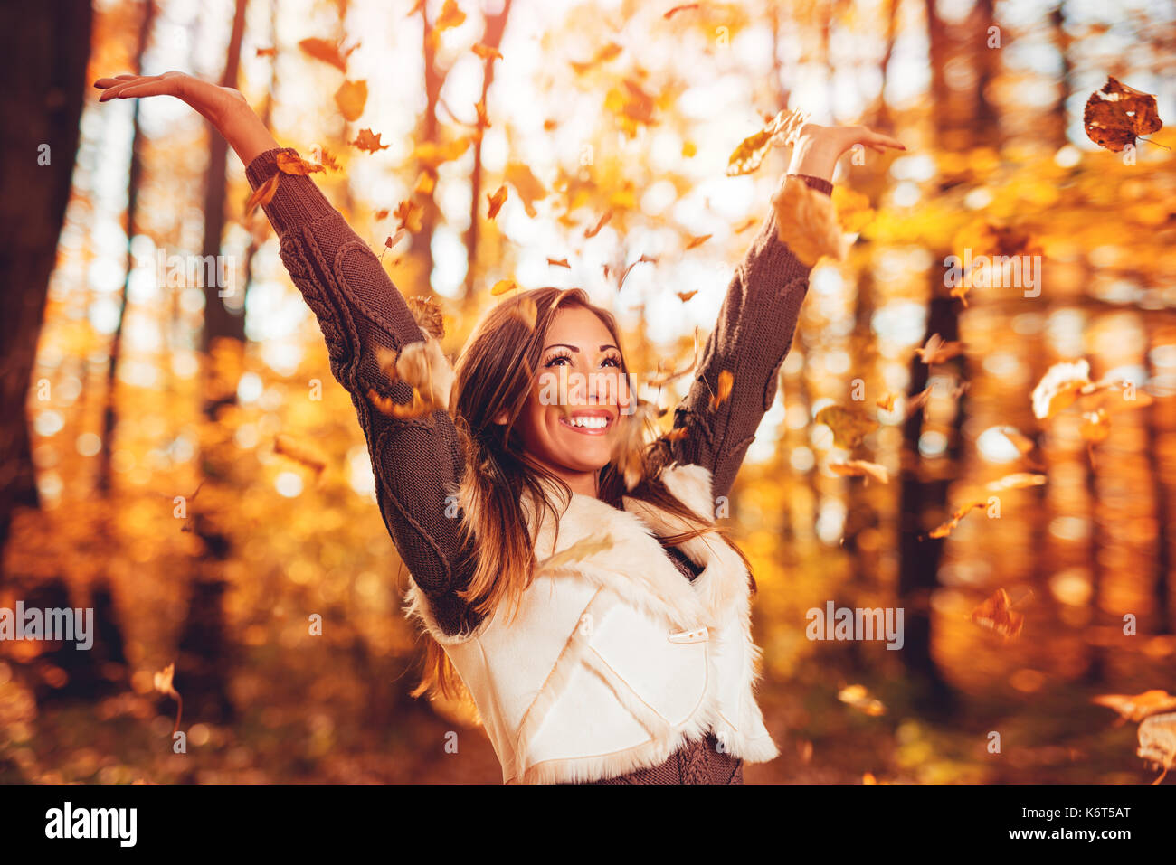 Allegro giovane donna divertirsi nella soleggiata foresta in autunno colori. Foto Stock