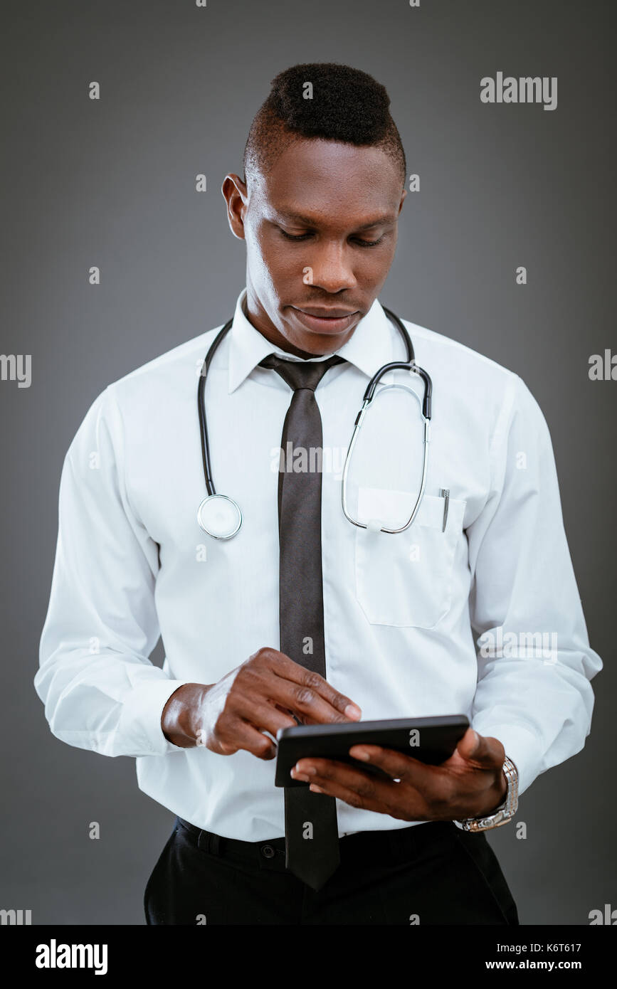 African medico con stetoscopio e permanente utilizzando digitale compressa. Foto Stock