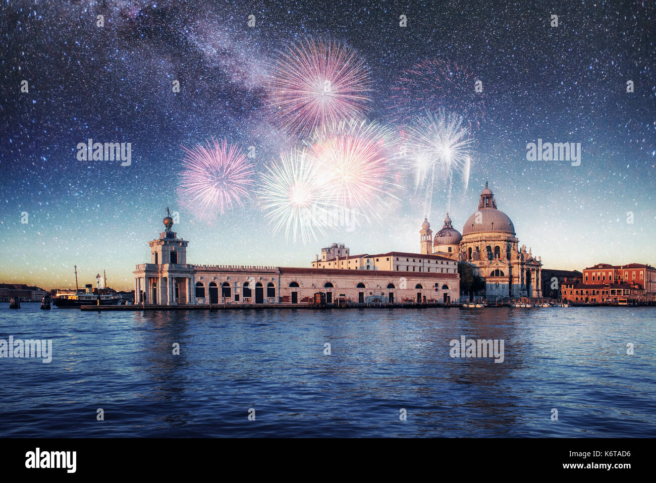 Illuminazione notturna degli edifici e barche vicino all'acqua. Venezia. photo greeting card. coloratissimi fuochi d'artificio sul cielo nero lo sfondo Foto Stock