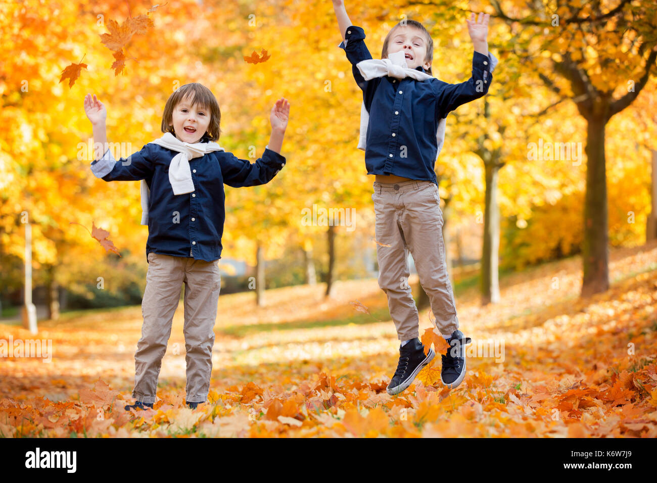 Dei bambini felici, ragazzo fratelli, giocando nel parco, gettando le foglie, giocando con foglie cadute in autunno Foto Stock