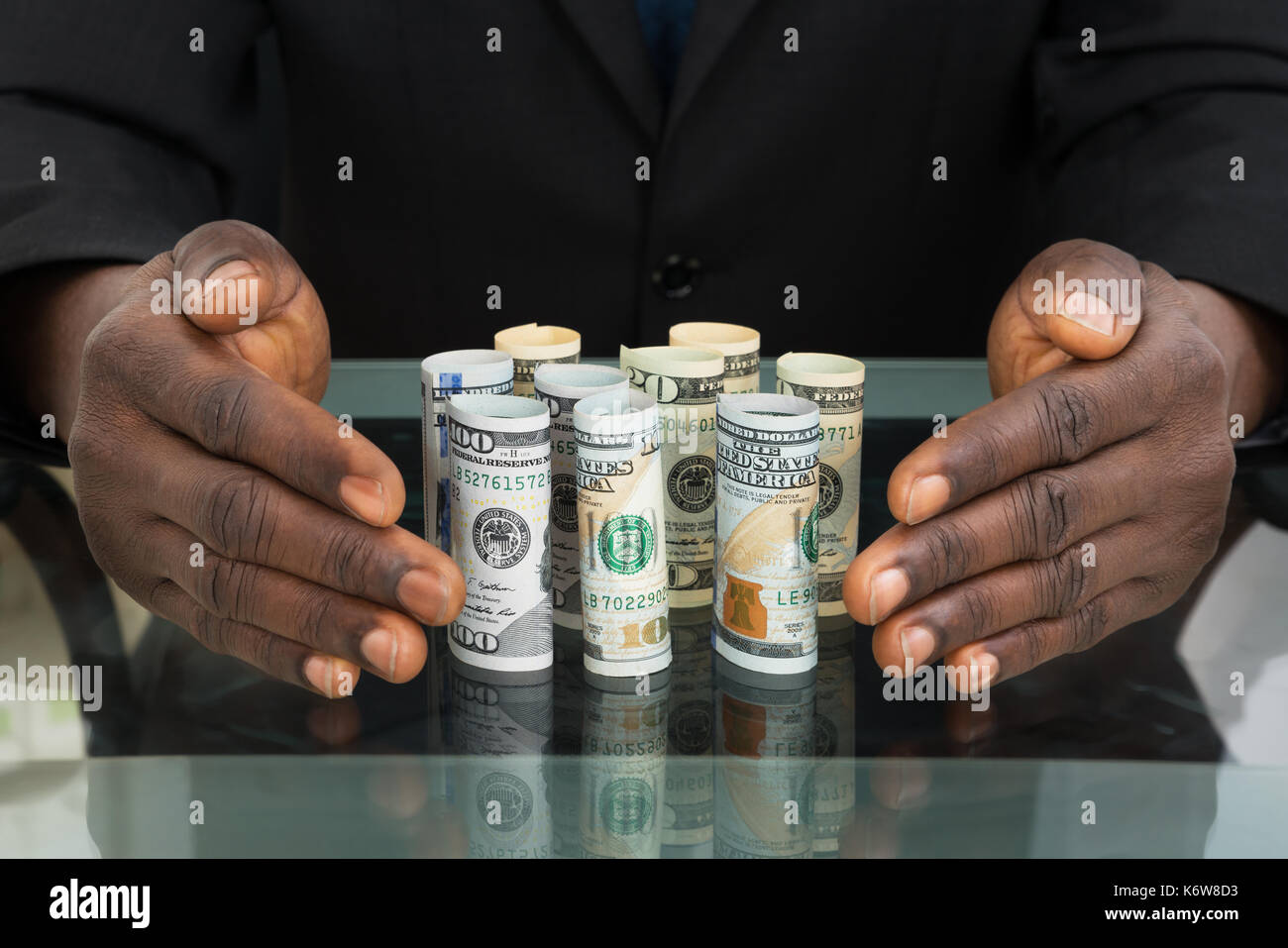 Close-up di imprenditore mani proteggere le banconote alla scrivania in vetro Foto Stock