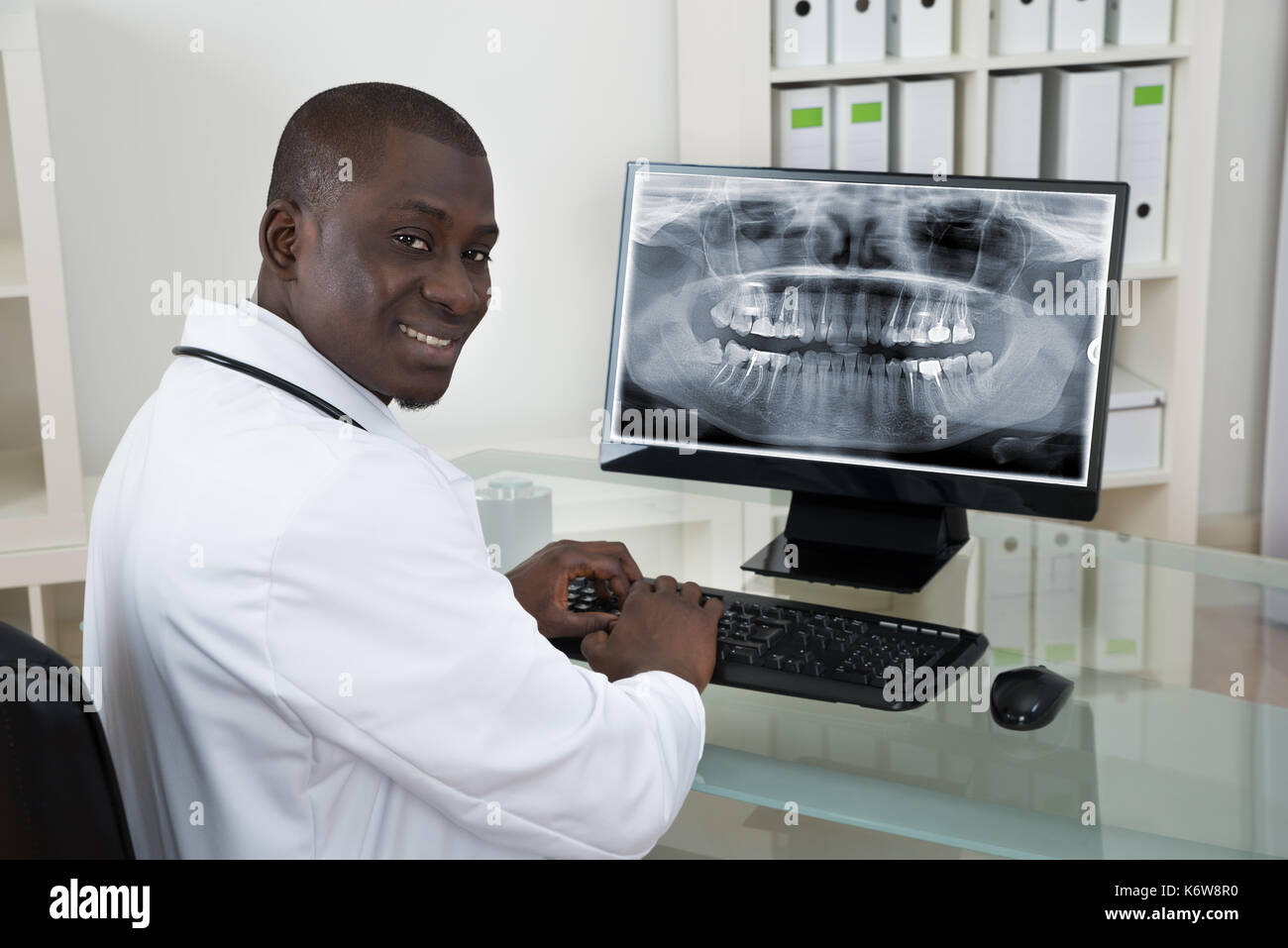I giovani africani felice dentista con denti x-ray sul computer alla reception Foto Stock