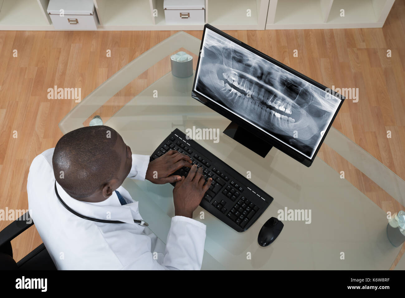 Giovane africana dentista analisi di raggi x denti sullo schermo del computer a scrivania Foto Stock