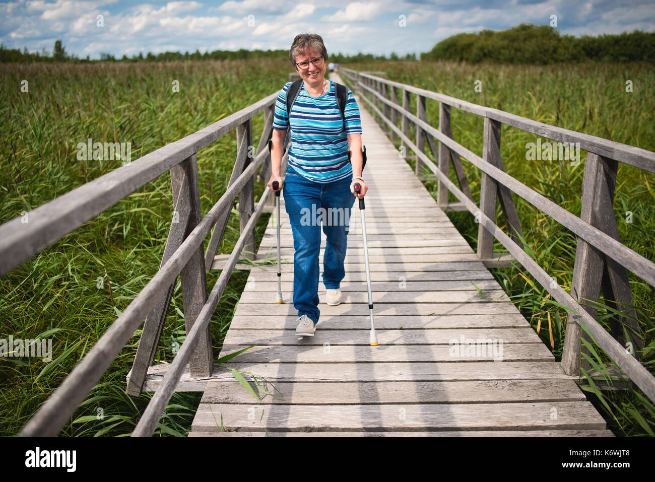 La donna anziana cammina sulle grondate sulla passerella Federsee, lago Federsee, patrimonio dell'umanità dell'UNESCO, Bad Buchau Foto Stock