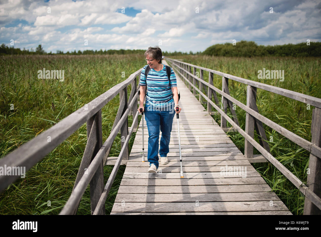 La donna anziana cammina sulle grondate sulla passerella Federsee, lago Federsee, patrimonio dell'umanità dell'UNESCO, Bad Buchau Foto Stock