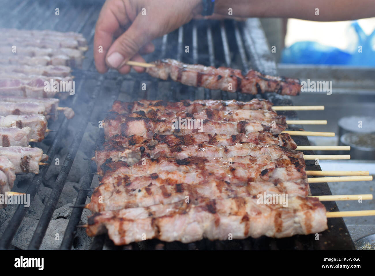 L'uomo la tostatura souvlaki spiedini di carne sul grill caldo. Foto Stock