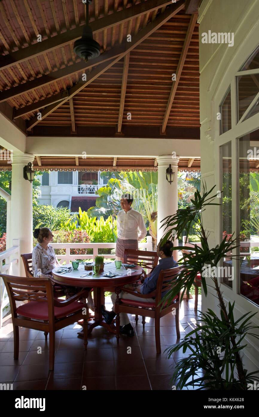 Laos, Luang Prabang, server con due clienti nella terrazza del ristorante dell'hotel Luang dire Residence Foto Stock