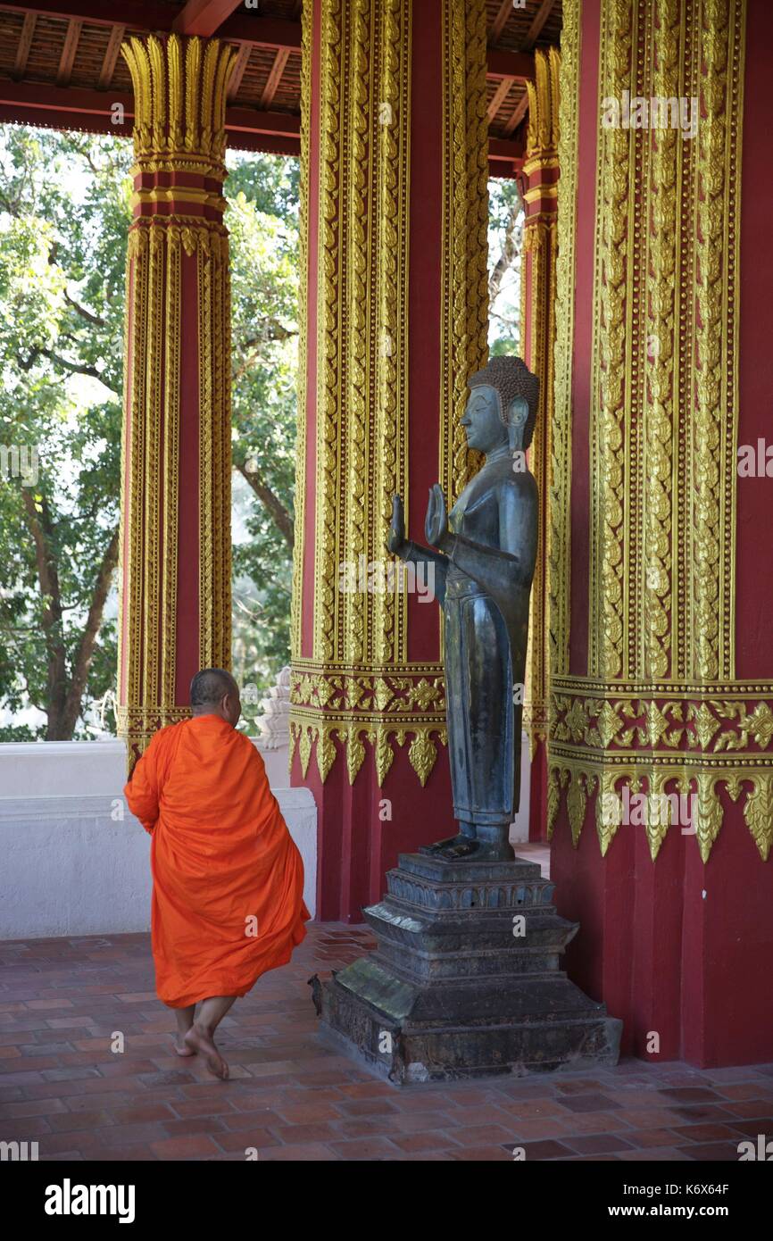 Laos, Vientiane, buddist monaco nell affronto robe di fronte ad una statua di Buddha nel tempio di Haw Pha Kaeo Foto Stock