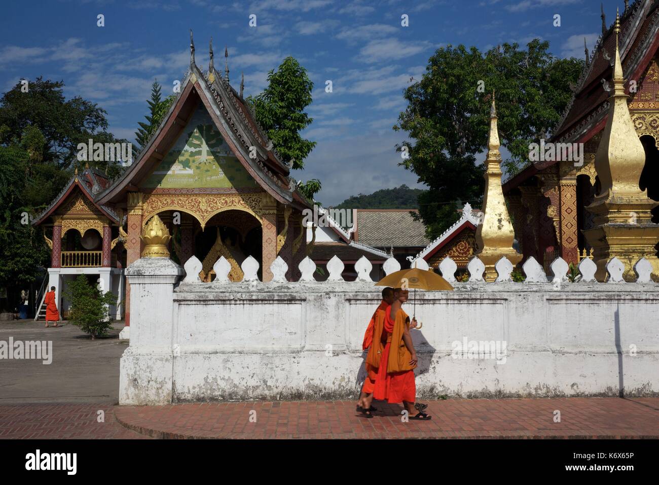 Laos, Luang Prabang, Asiama, giovani monaci buddists in veste di zafferano sotto gli ombrelloni di fronte al tempio Iva Sene Souk haram Foto Stock