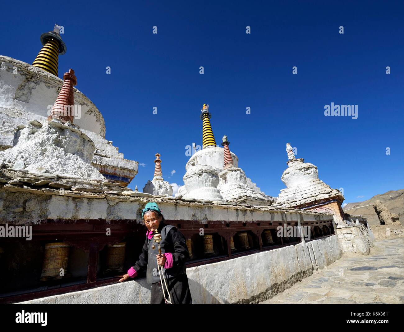 India, dello Stato del Jammu e Kashmir, Himalaya, Ladakh, Indus Valle, monastero buddista di Lamayuru (Yungdrung), vecchia donna con la preghiera ruota in prossimità stupa (chorten) Foto Stock