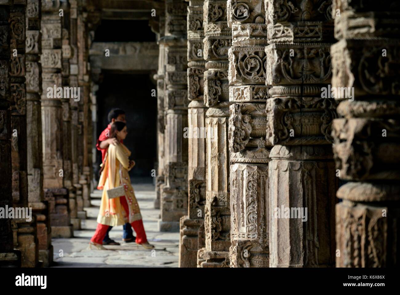 India Delhi Qutb Minar (Qutub, Qutab) elencati come patrimonio mondiale dall' UNESCO, il XIII secolo minareto, 72m, 14m diametro alla base, Indiano giovane camminando tra le colonne Foto Stock