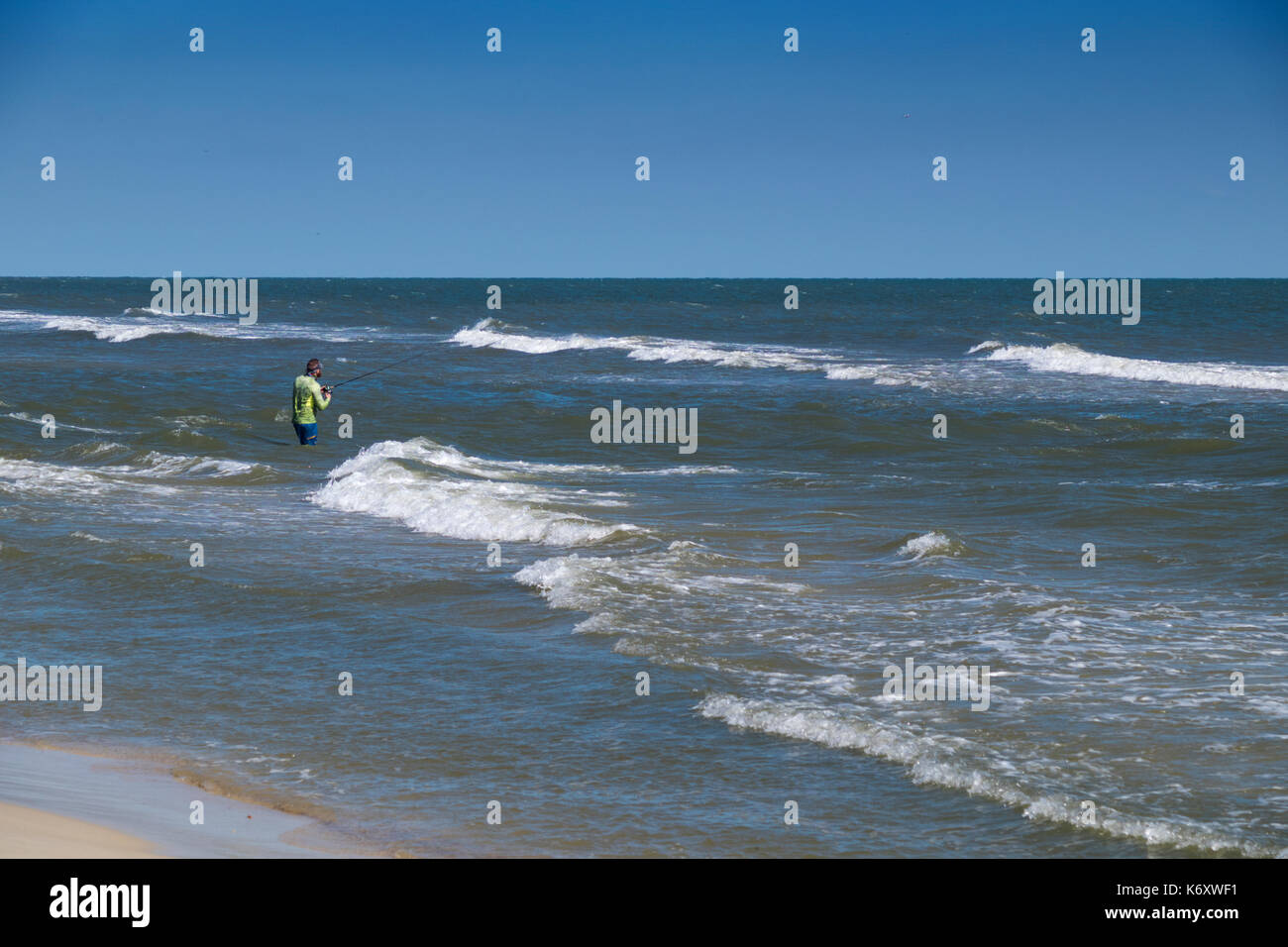 Pescatore solitario surf casting nel Golfo del Messico, vicino a Gulf Shores, Alabama. Foto Stock