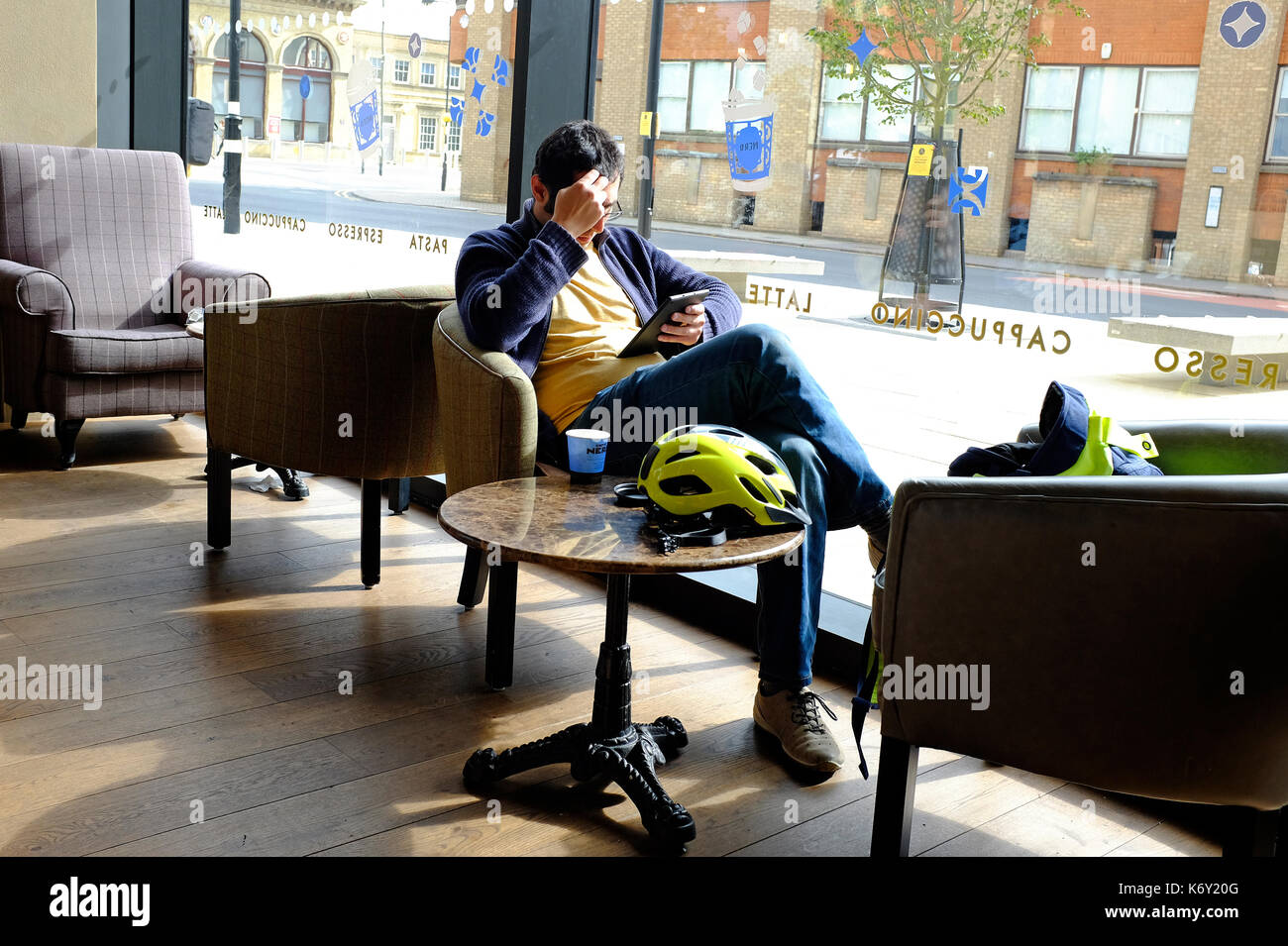 Giovane maschio persona seduta in cafe utilizzando computer tablet Foto Stock