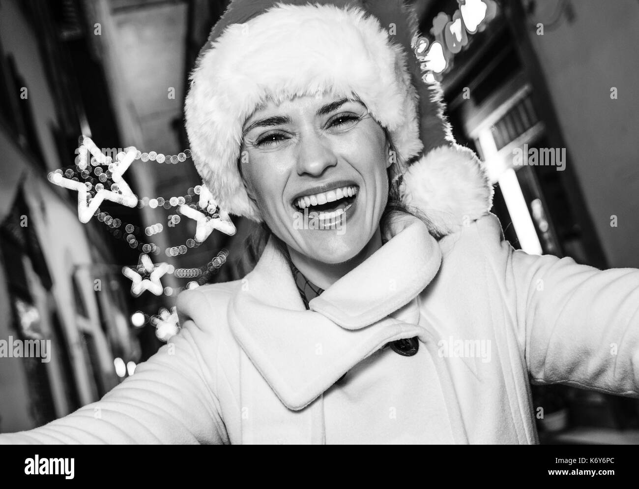 Viaggio pieno di ispirazione al tempo di Natale a Firenze. Felice giovane donna nel cappello di Natale a Firenze, Italia tenendo selfie Foto Stock