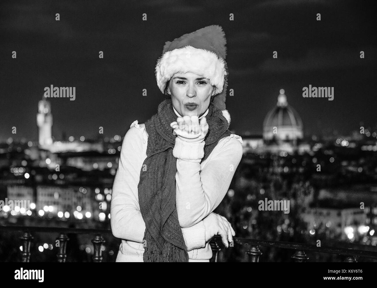 Viaggio pieno di ispirazione al tempo di Natale a Firenze. sorridente giovane donna nel cappello di Natale a piazzale Michelangelo a Firenze, Italia soffiando aria k Foto Stock