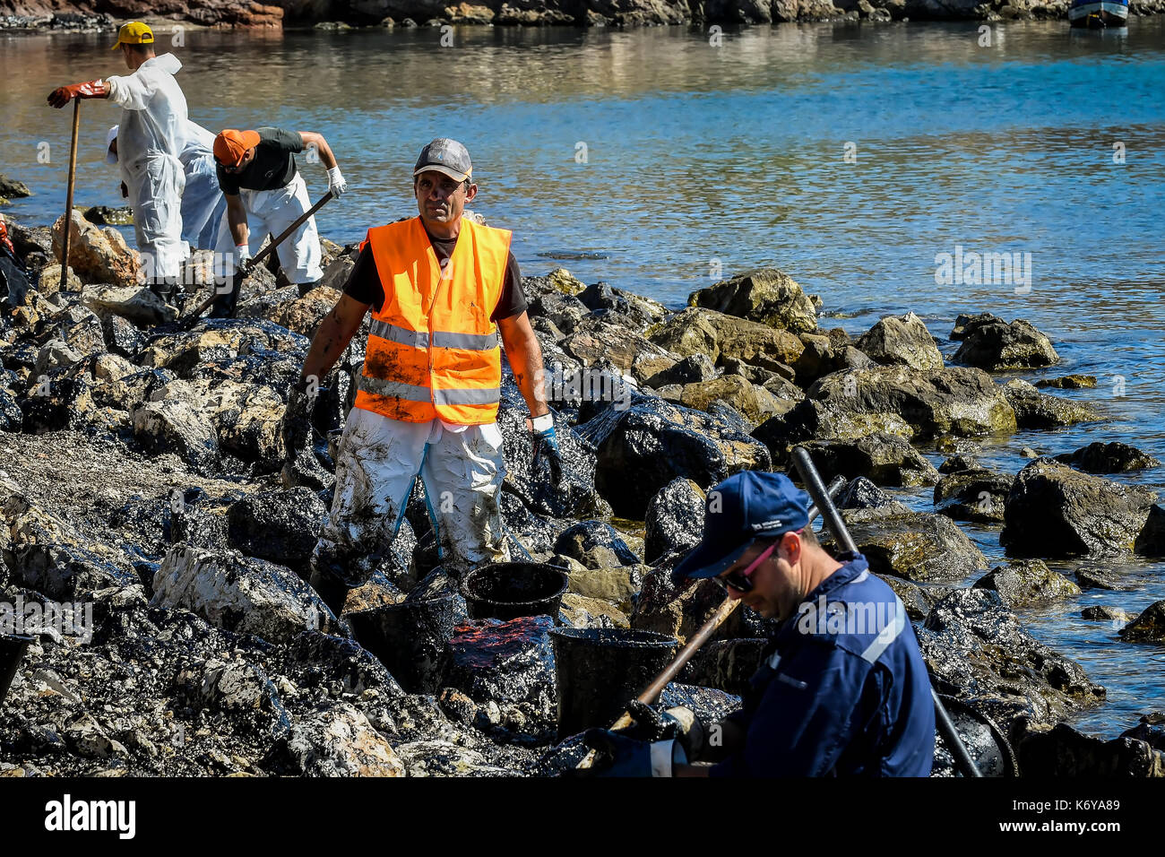 Salumi, Atene, Grecia - Settembre 13, 2017: i lavoratori provare a pulire l'olio che è lavato a terra, su una spiaggia di isola di Salamina vicino ad Atene, dopo un vecchio ta Foto Stock
