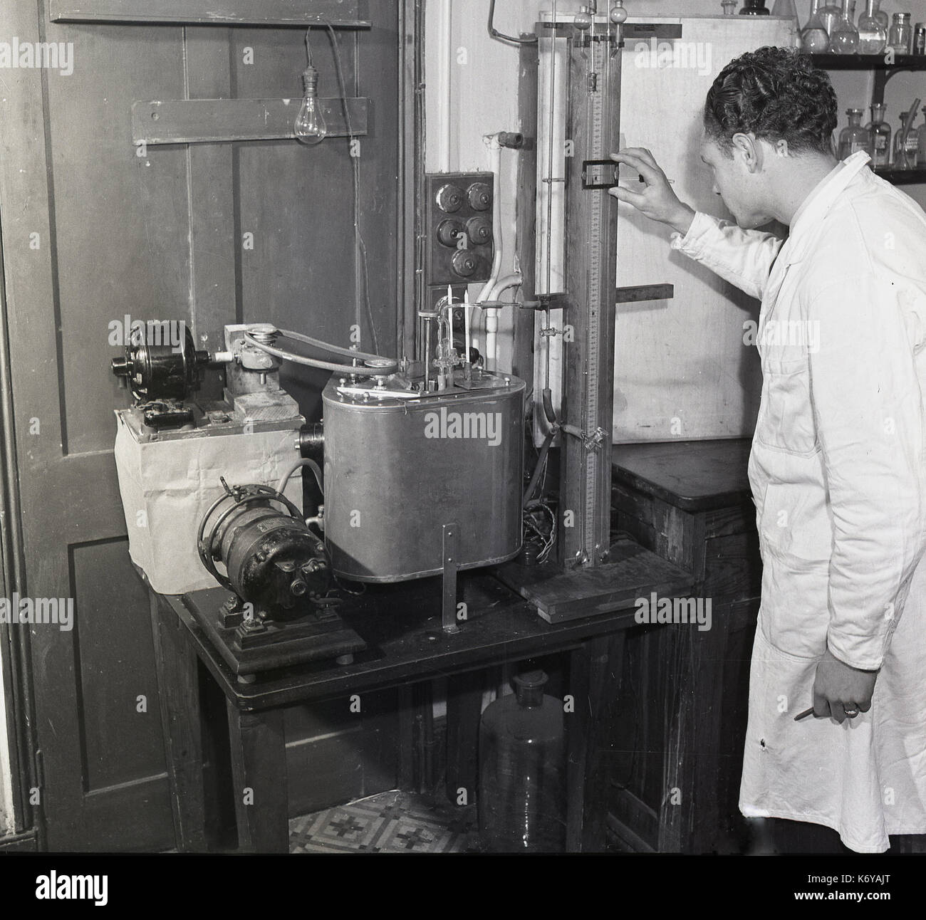 anni '1950, storica, ricerca alimentare, uno scienziato in un cappotto bianco che usa l'apparato dell'epoca per studiare le proprietà reologiche del cioccolato. Foto Stock