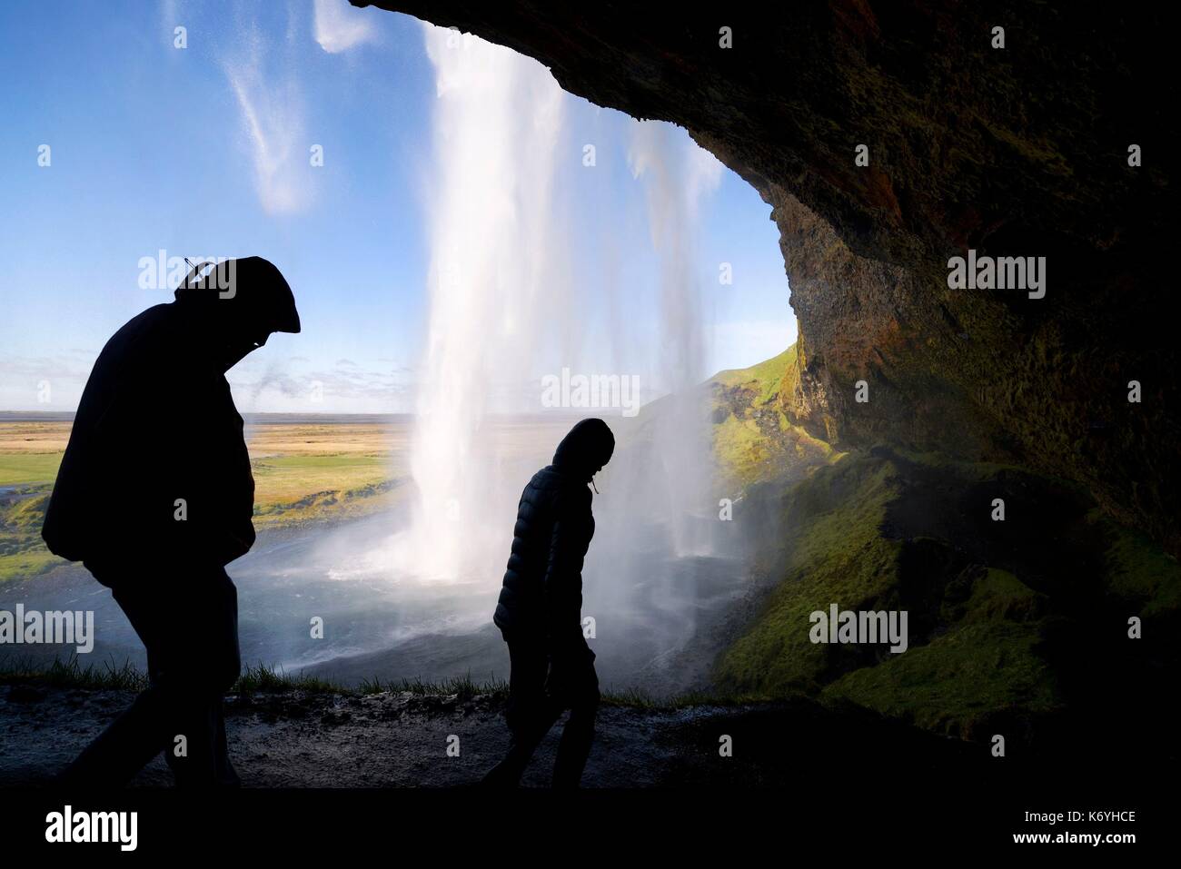 L'Islanda, regione Sudurland, Seljalandsfoss cascata, silhouette di persone su un percorso che passa dietro la cascata Foto Stock