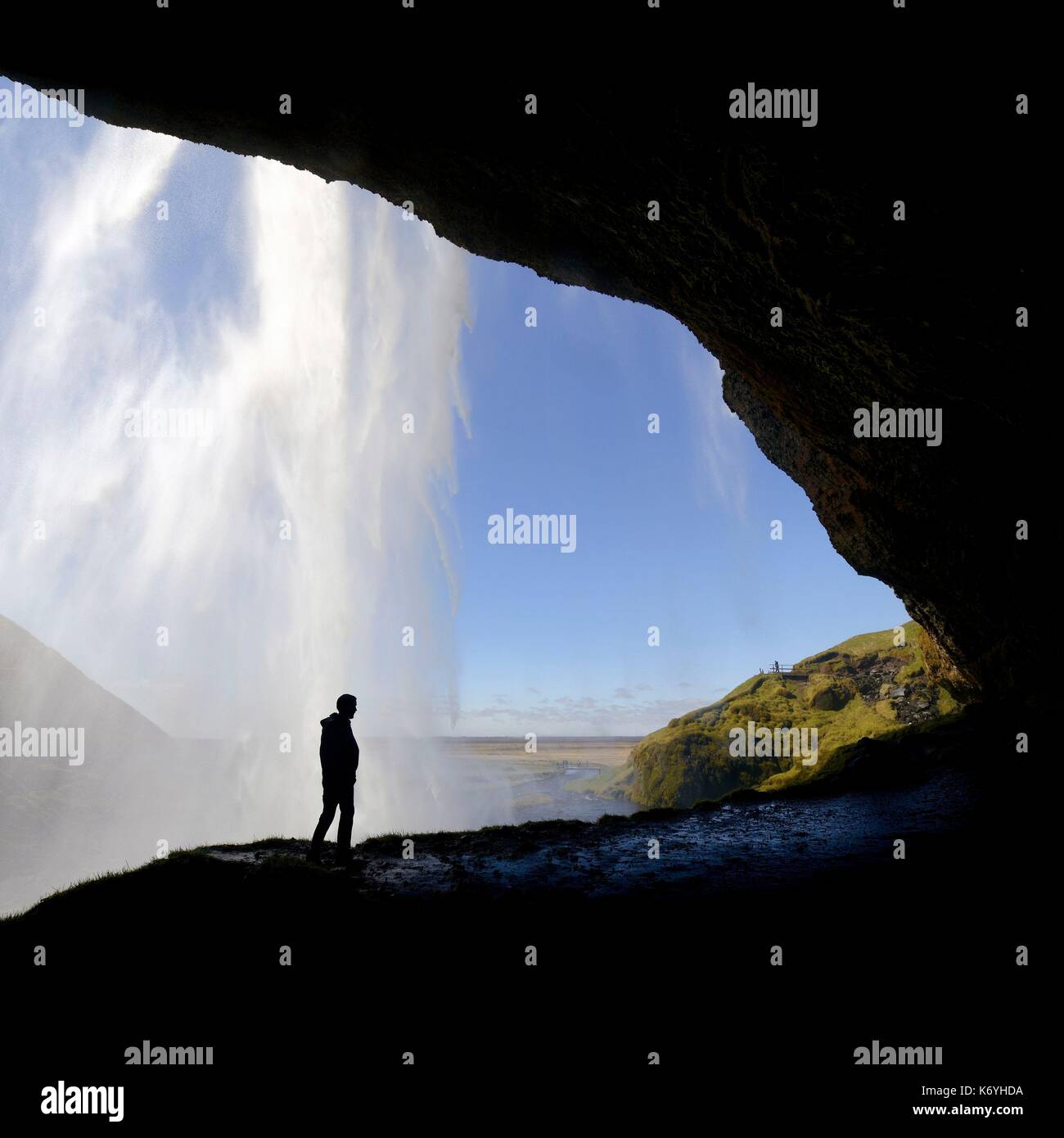 L'Islanda, regione Sudurland, Seljalandsfoss cascata, silhouette di un uomo su un percorso che passa dietro la cascata Foto Stock
