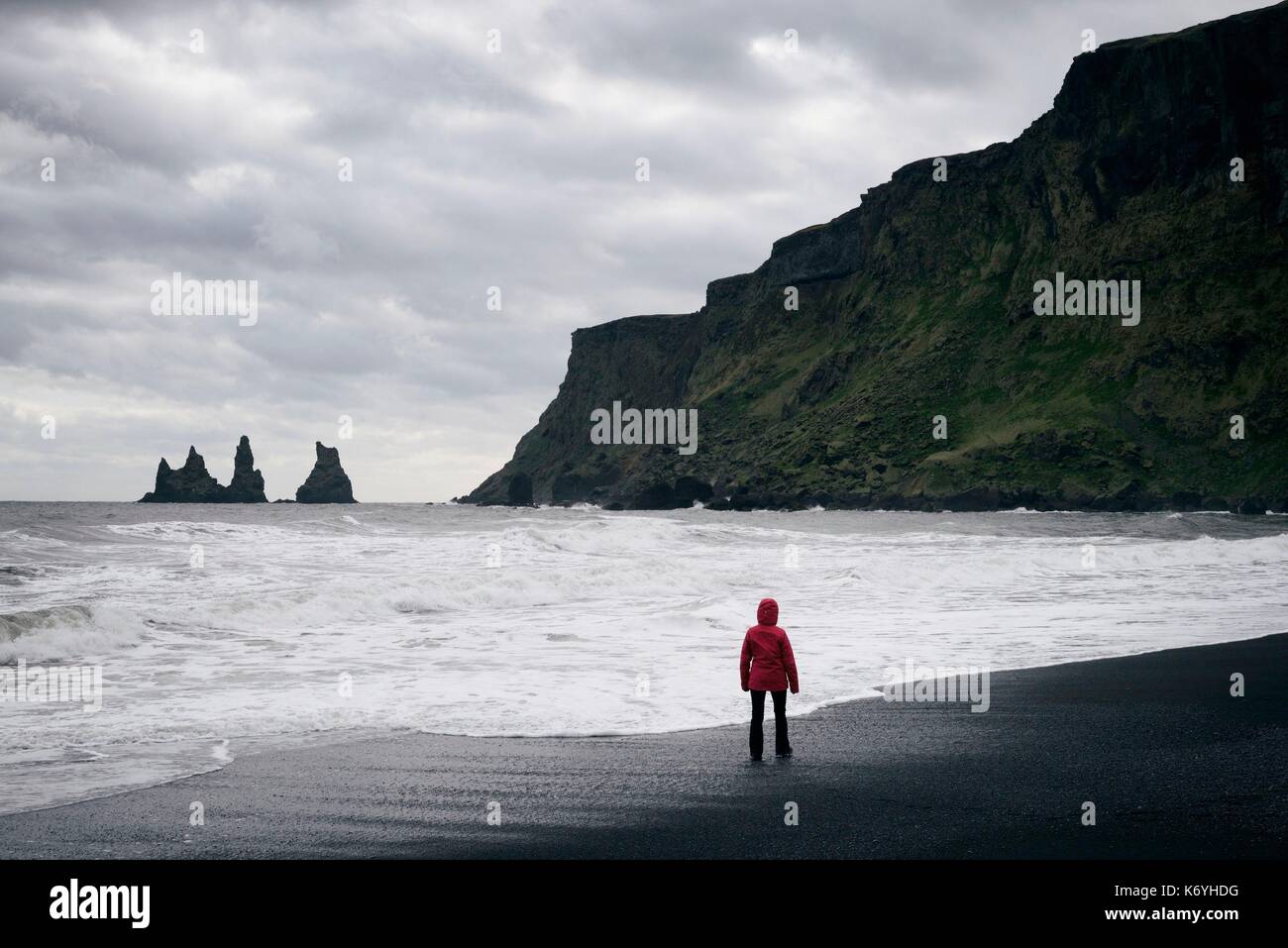 L'Islanda, regione Sudurland, Vik mi Myrdal, Vik beach, donna sulla spiaggia di sabbia nera e il mare Reynisdrangur pile Foto Stock