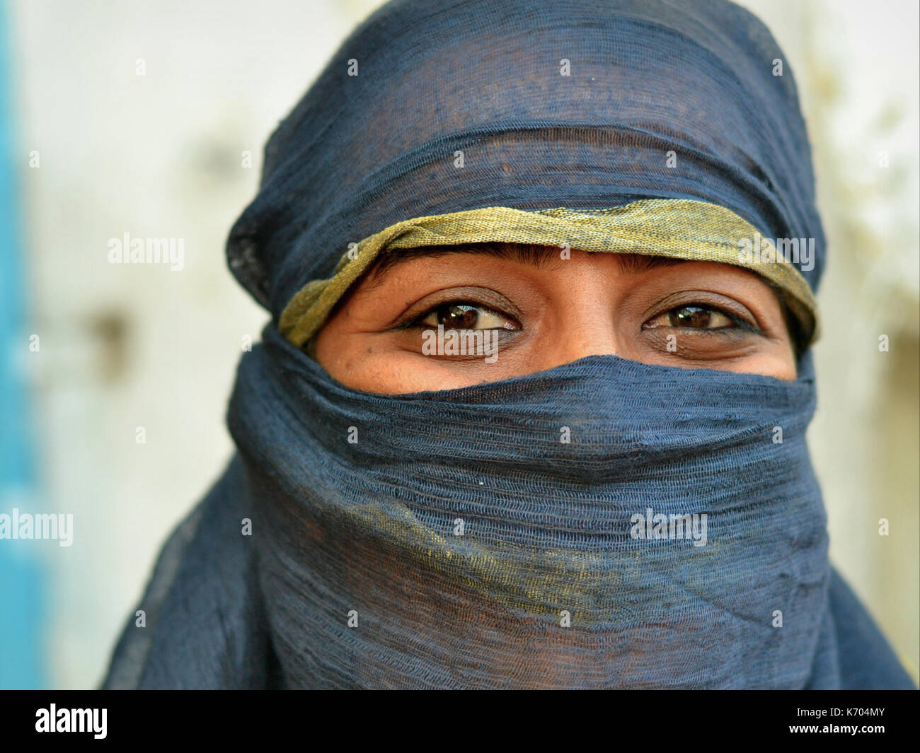 Indian Muslimah con occhi sorridenti indossa un velo nero semi-velato e posa per la macchina fotografica. Foto Stock