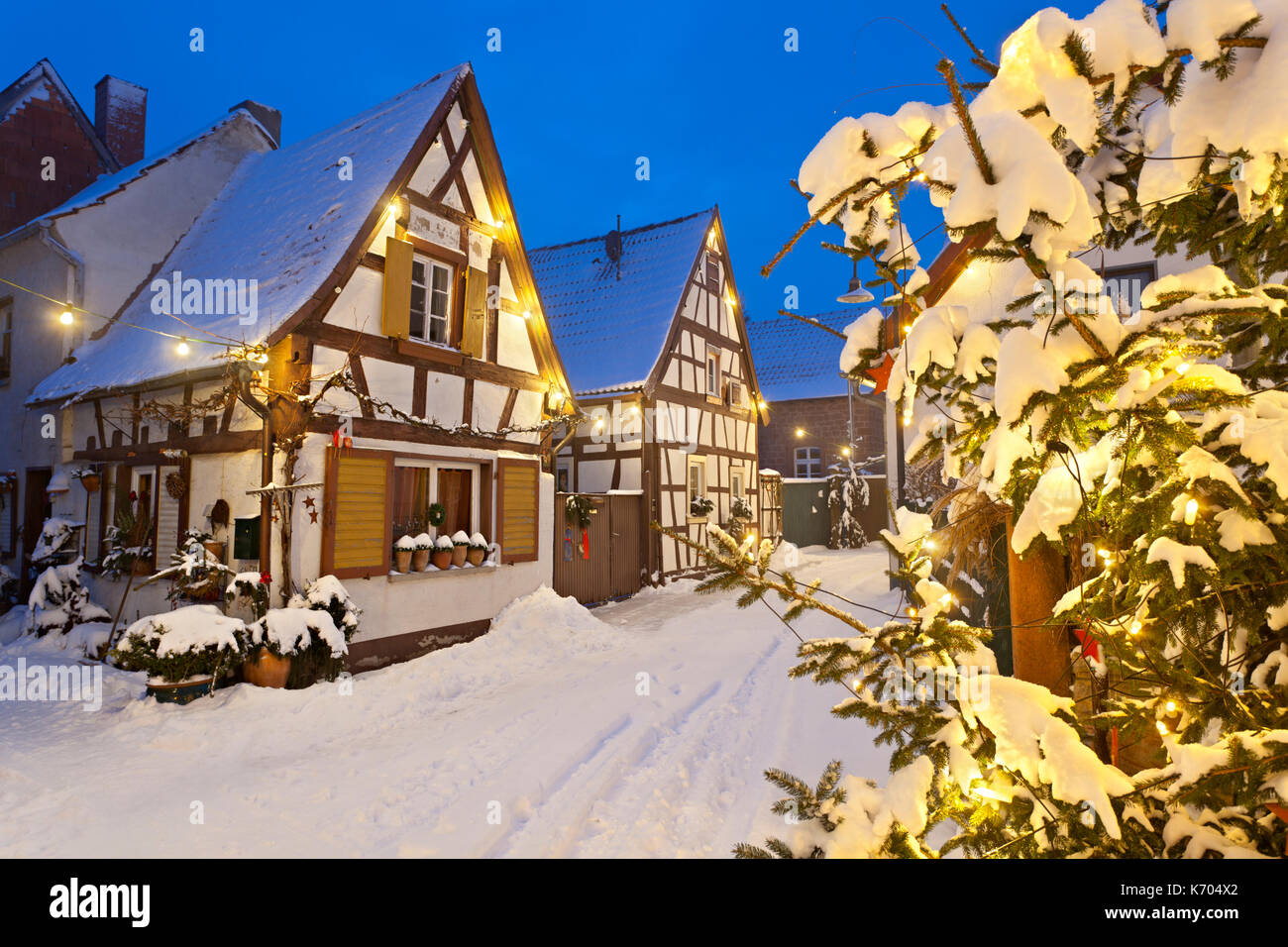 Un vecchio villaggio di strada con semi-case con travi di legno e le luci di Natale di notte durante la nevicata a Lachen, neustadt an der Weinstrasse, Germania. Foto Stock