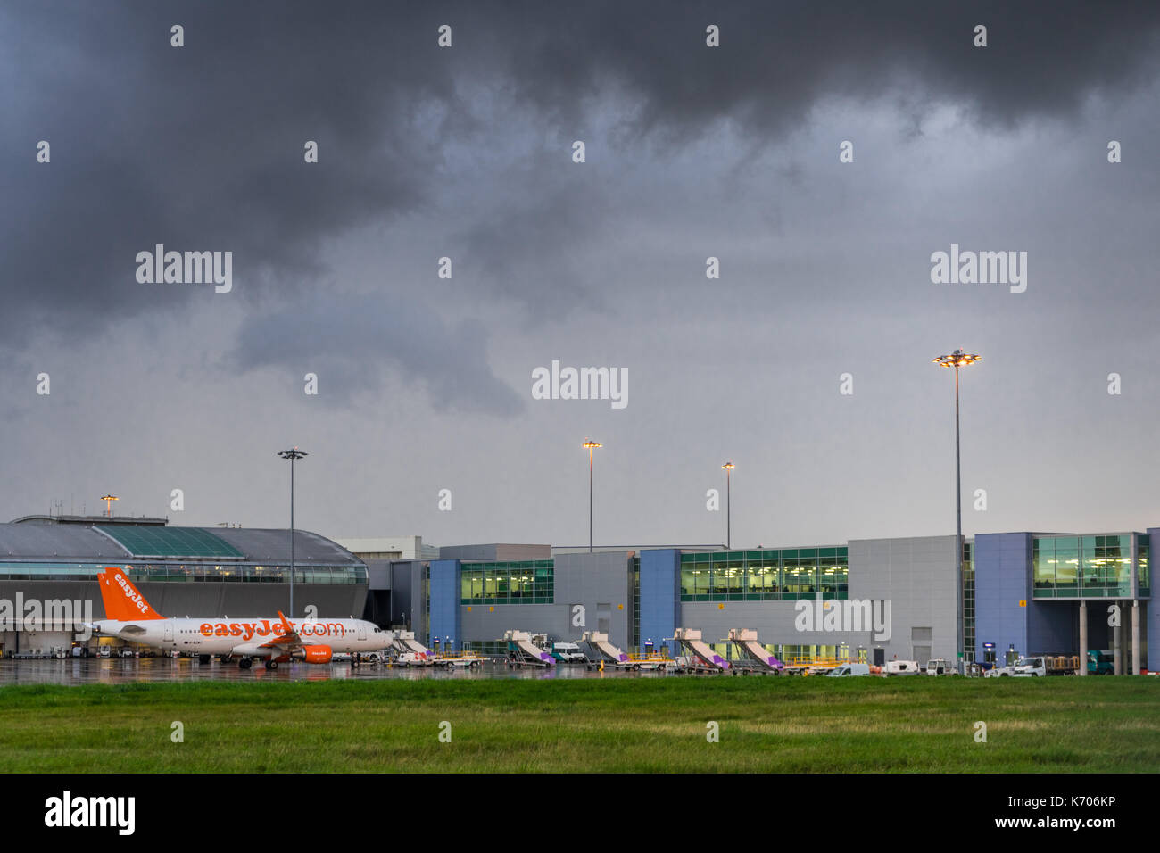 Tempesta drammatico nuvole sopra l'Aeroporto di Luton (LTN) con un piano di Easyjet su asfalto umido in 2017, Luton, Inghilterra, Regno Unito Foto Stock