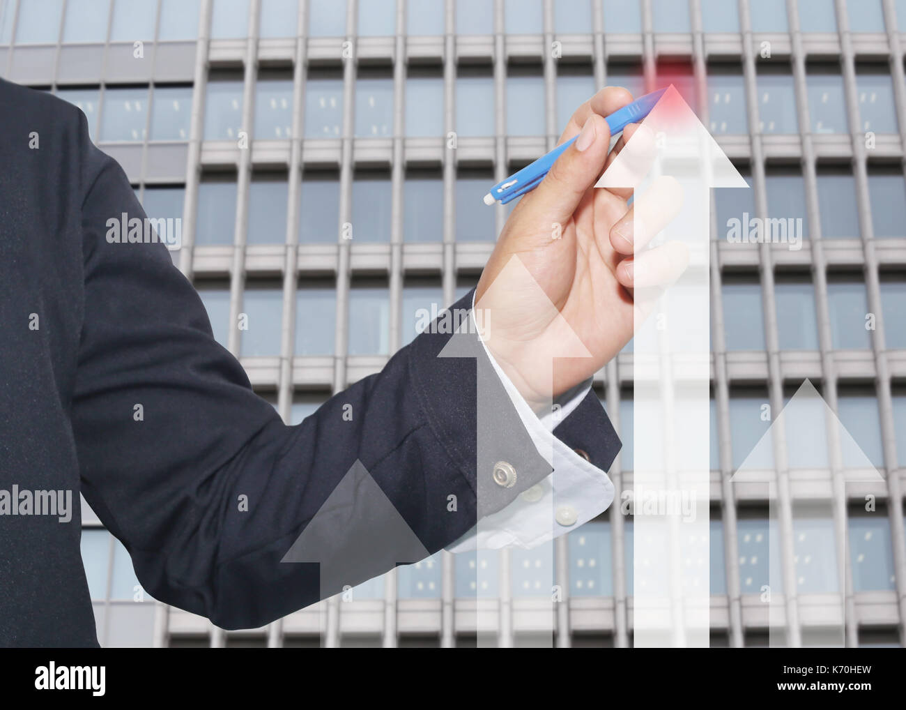 Mano di proprietari utilizzando una penna blu rivolta alla freccia superiore grafico sulla parete di vetro sullo sfondo di edifici alti,concetto di investimenti e profitti. Foto Stock