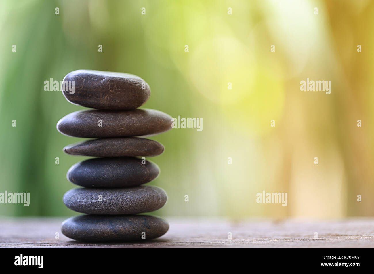 Equilibrio pietra sul pavimento in legno e morbida luce del sole nel giardino la nozione di meditazione e spa. Foto Stock