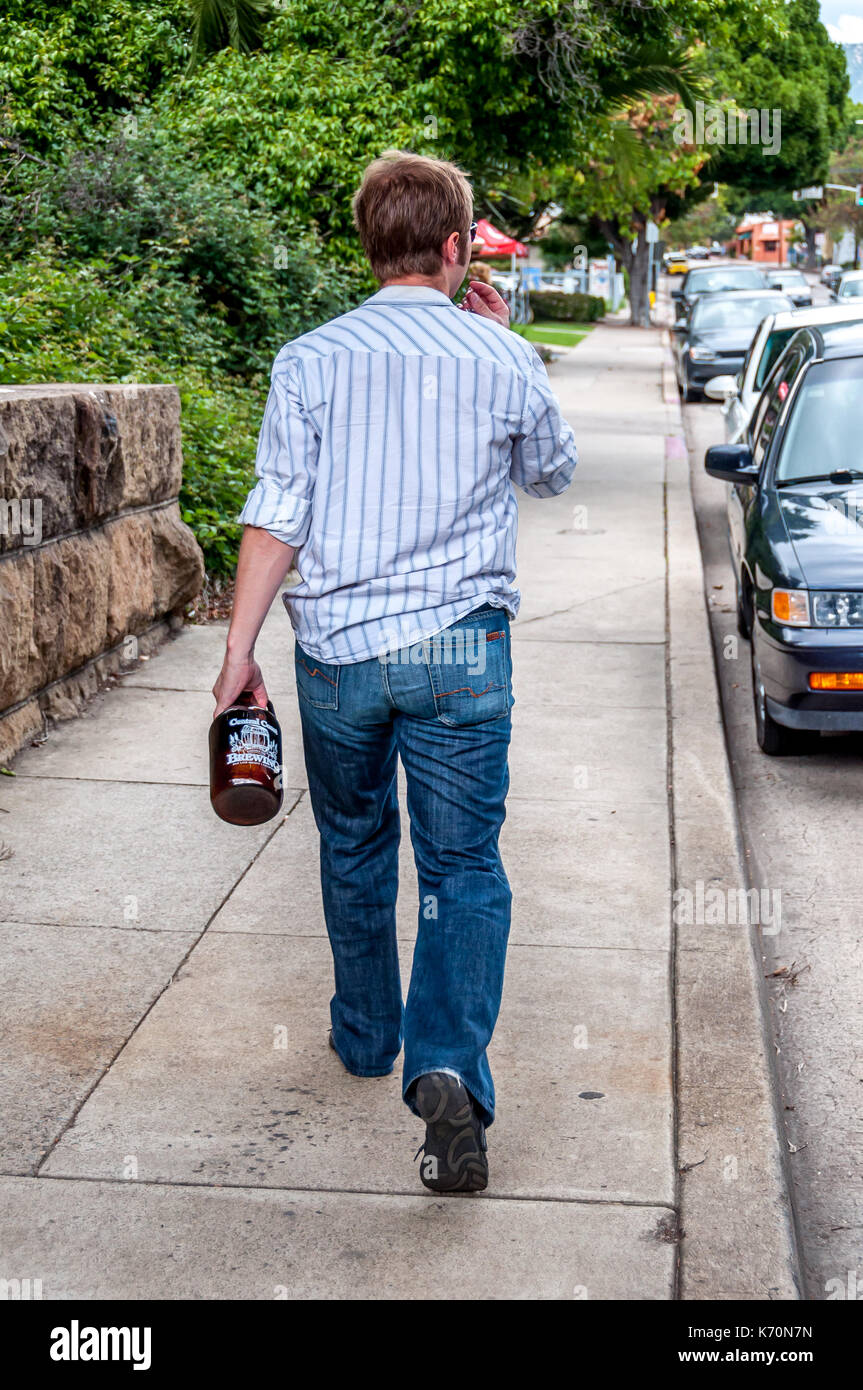 Un uomo cammina home portando una birra growler riempito dall'intruglio locale pub in San Luis Obispo, California, il centro di micro brewing sulla Costa Centrale Foto Stock