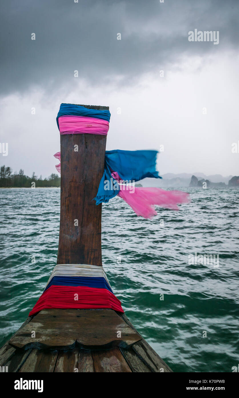 La parte anteriore di una barca dalla lunga coda con la preghiera sciarpe guardando verso terra in la distanza e le sciarpe battenti nel vento, il mare delle Andamane, Krabi, Thailandia Foto Stock