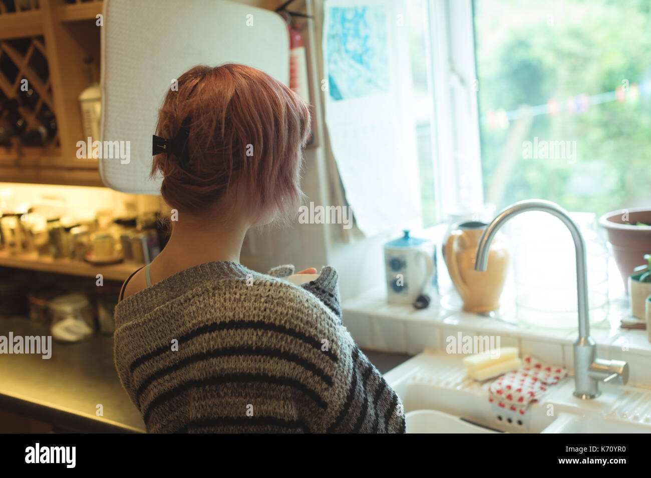 Vista posteriore della giovane donna in piedi in cucina a casa Foto Stock